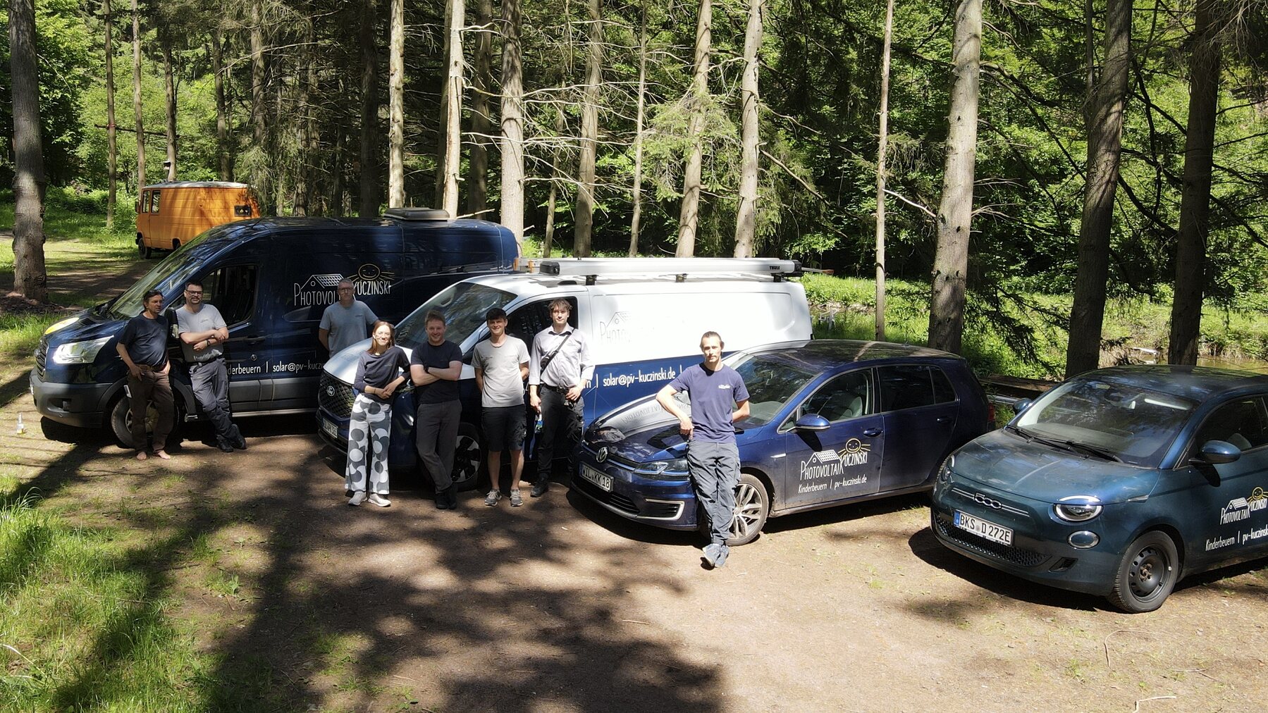 Team von Photovoltaik Kuczinski mit Firmenfahrzeugen im Wald